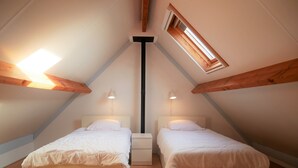 A room with two beds, a central light fixture, and a skylight.