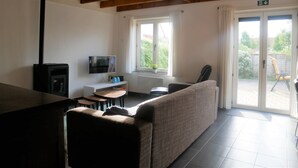 A modern living room with a sofa, a TV, a small table, and a window with curtains.