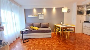 A compact room with a bed, a dining table, and chairs. There is a kitchen area with appliances and a clock on the wall. - Temporary Apart. Excellent location in the historic center of Cordoba! One bedroom (Córdoba)