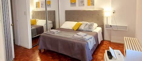 A modern bedroom with a large bed, a heater, and a mirror.