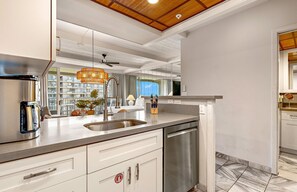 Una cocina moderna con un lavamanos de acero inoxidable, lavavajillas y techo de madera.