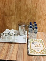 Una bandeja con una jeringa de metal, varios frascos de vidrio y botellas de agua sobre una superficie de madera.