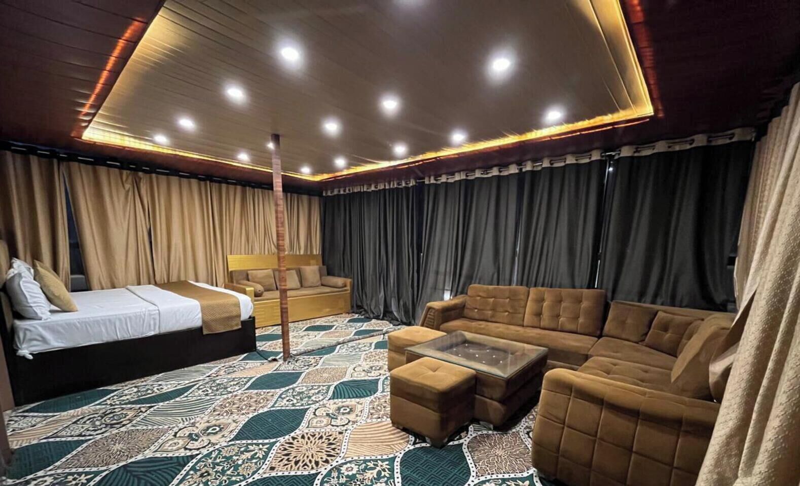 Une pièce spacieuse avec un grand lit, un canapé, une table basse et un tapis à motifs.