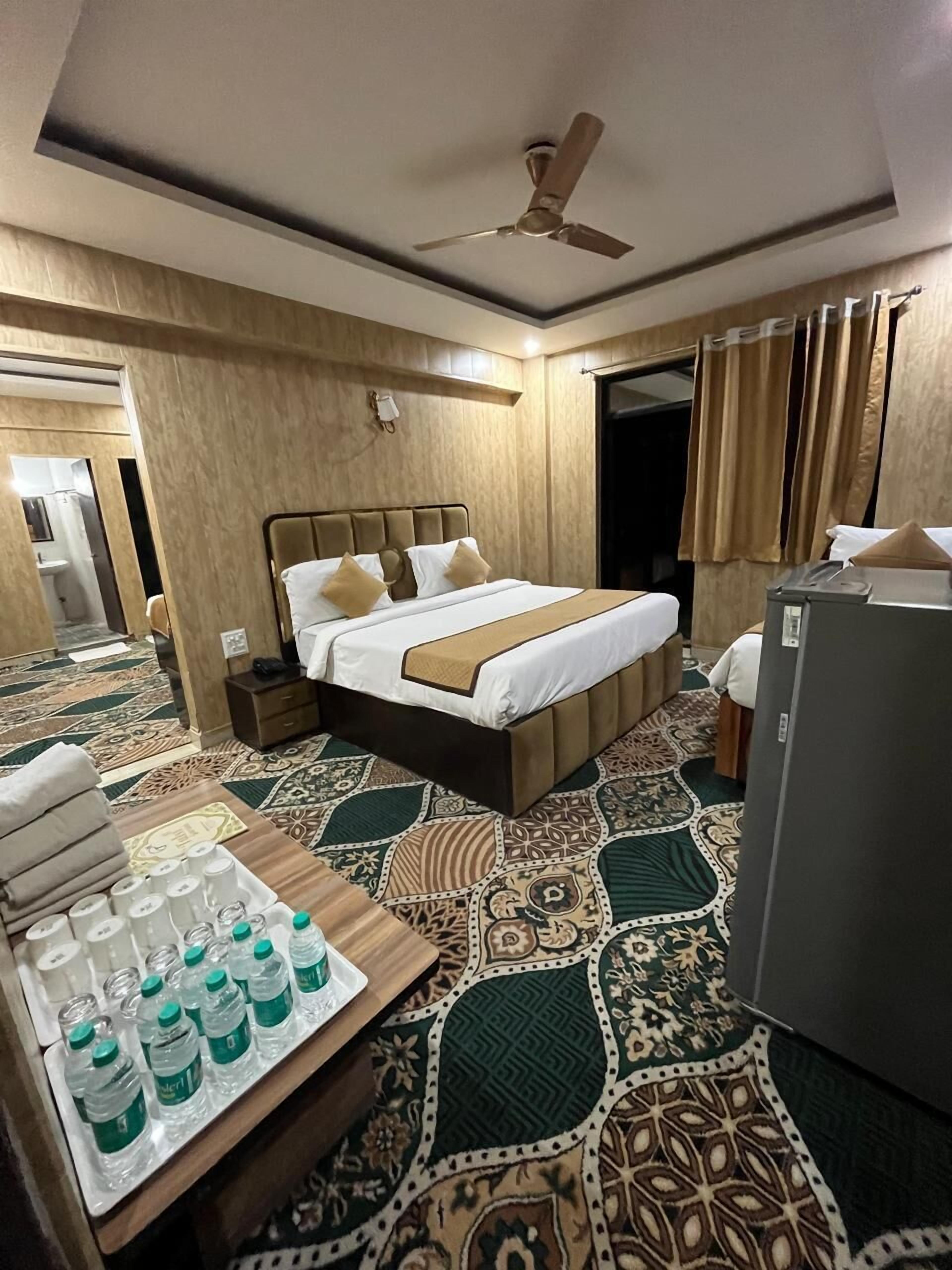 A hotel room with a bed, bedside table, and a refrigerator.