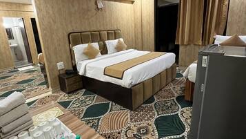 A hotel room with a bed, bedside table, and a refrigerator.