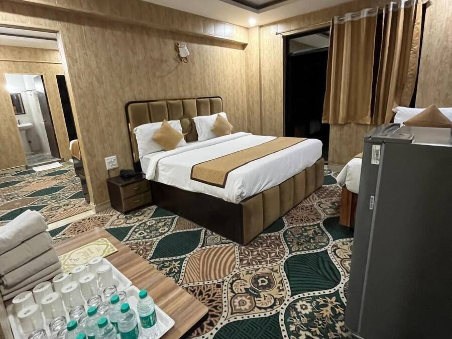 A hotel room with a bed, bedside table, and a refrigerator.