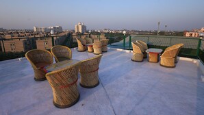Terraza en la azotea con mobiliario de mimbre y vista panorámica de la ciudad.