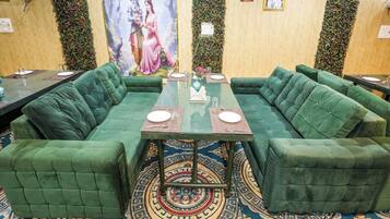 Un salón de conferencias con una mesa de vidrio, sofás tapizados en verde y una alfombra estampada.