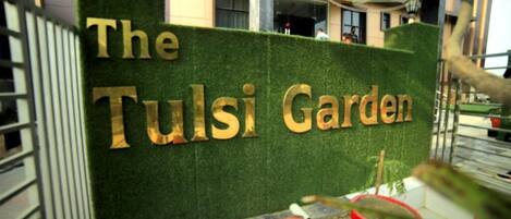 A sign for "The Tulsi Garden" with a green background and gold lettering.