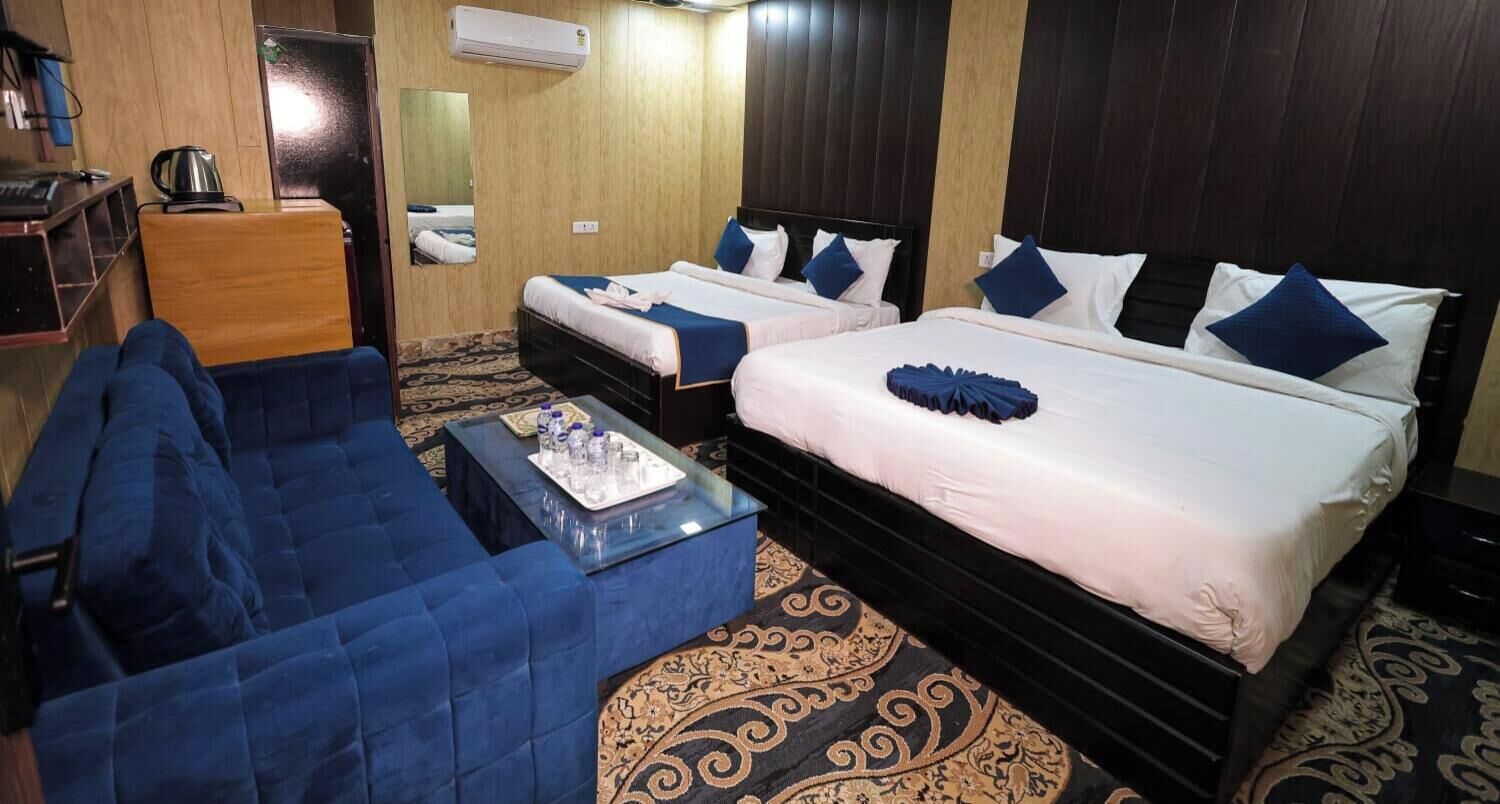 Una habitación de hotel con dos camas, un sofá, una mesa de centro y un espejo.
