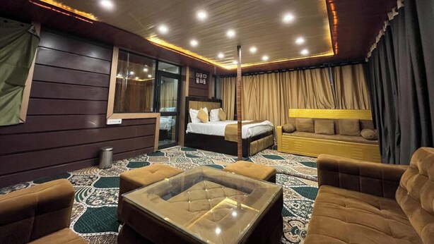 Una habitación de hotel con una cama, un sofá, una mesita de vidrio y una alfombra estampada.