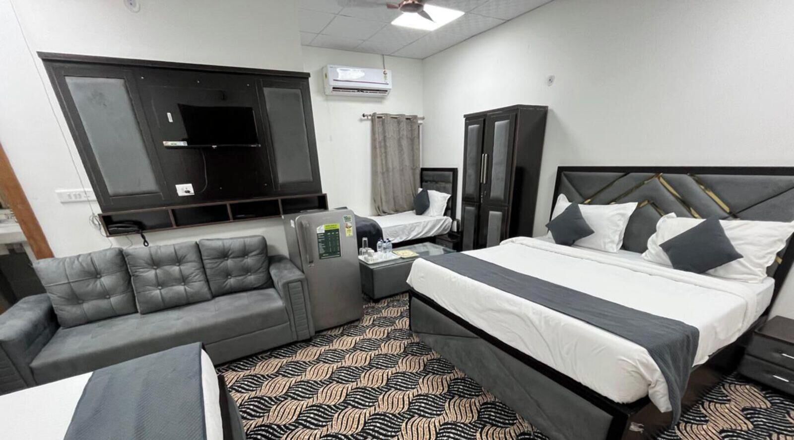 A hotel room with a bed, a sofa, a desk, and a TV.