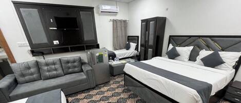 A hotel room with a bed, a sofa, a desk, and a TV.