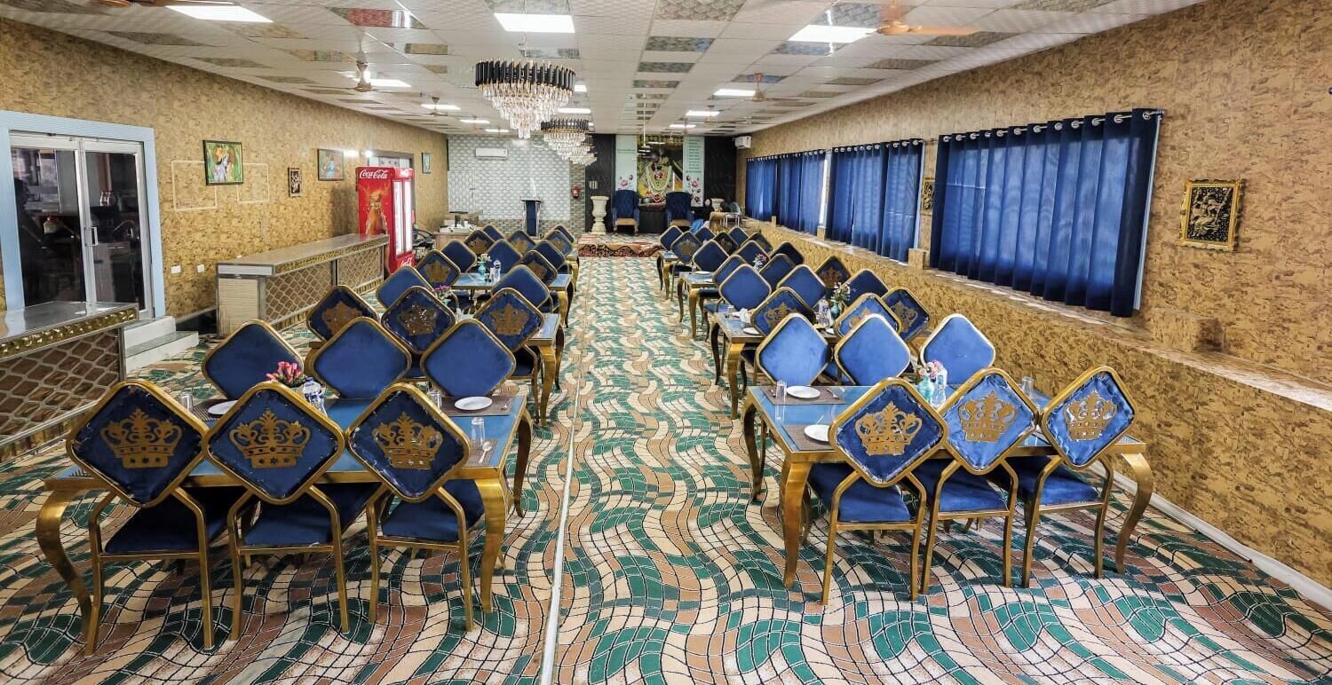 Un salón de conferencias con mesas y sillas dispuestas en filas, una alfombra estampada y una araña de cristal.