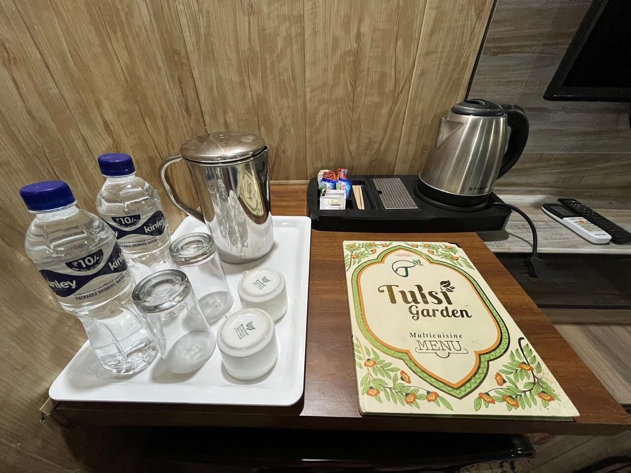 A tray with bottled water, a teapot, and small containers, alongside a menu for Tusi Garden.