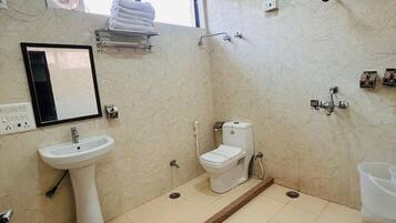 Un baño con lavamanos pedestal, inodoro, ducha y una ventana sobre el lavamanos.