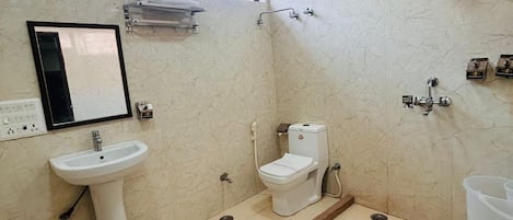 Ein Badezimmer mit einem Standwaschbecken, Toilette, Dusche und einem Fenster über dem Waschbecken.