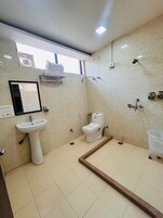 Un baño con lavamanos pedestal, inodoro, ducha y una ventana sobre el lavamanos.