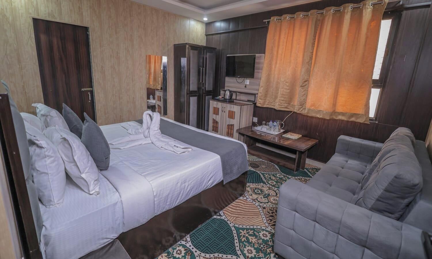 A hotel room with two beds, a sofa, a TV, and a small table.