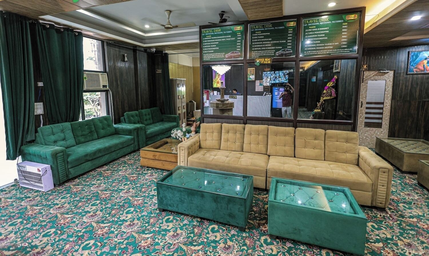 A hotel lobby with a green sofa, a beige sofa, and two green coffee tables.