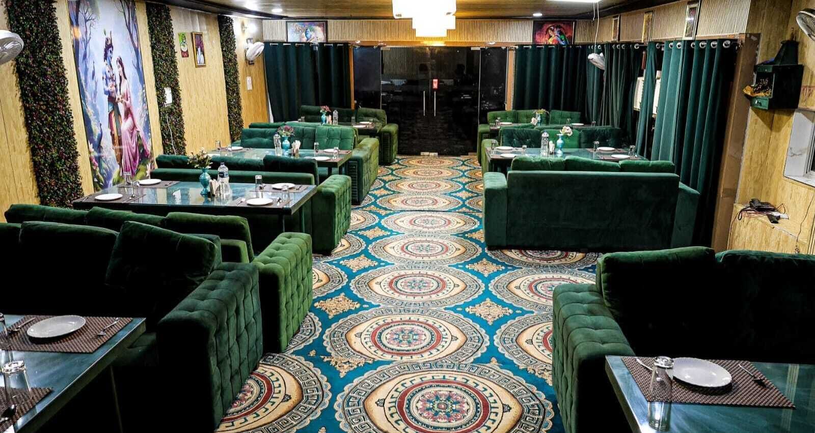A restaurant with green upholstered booths and tables, a patterned carpet, and a mural on the wall.