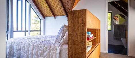 Een slaapkamer met een bed, een houten boekenkast en uitzicht buiten door een raam.