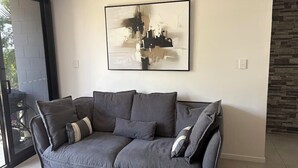Ein modernes Wohnzimmer mit einem grauen Sofa, einem großen abstrakten Gemälde und einer Wand mit Steinakzenten.
