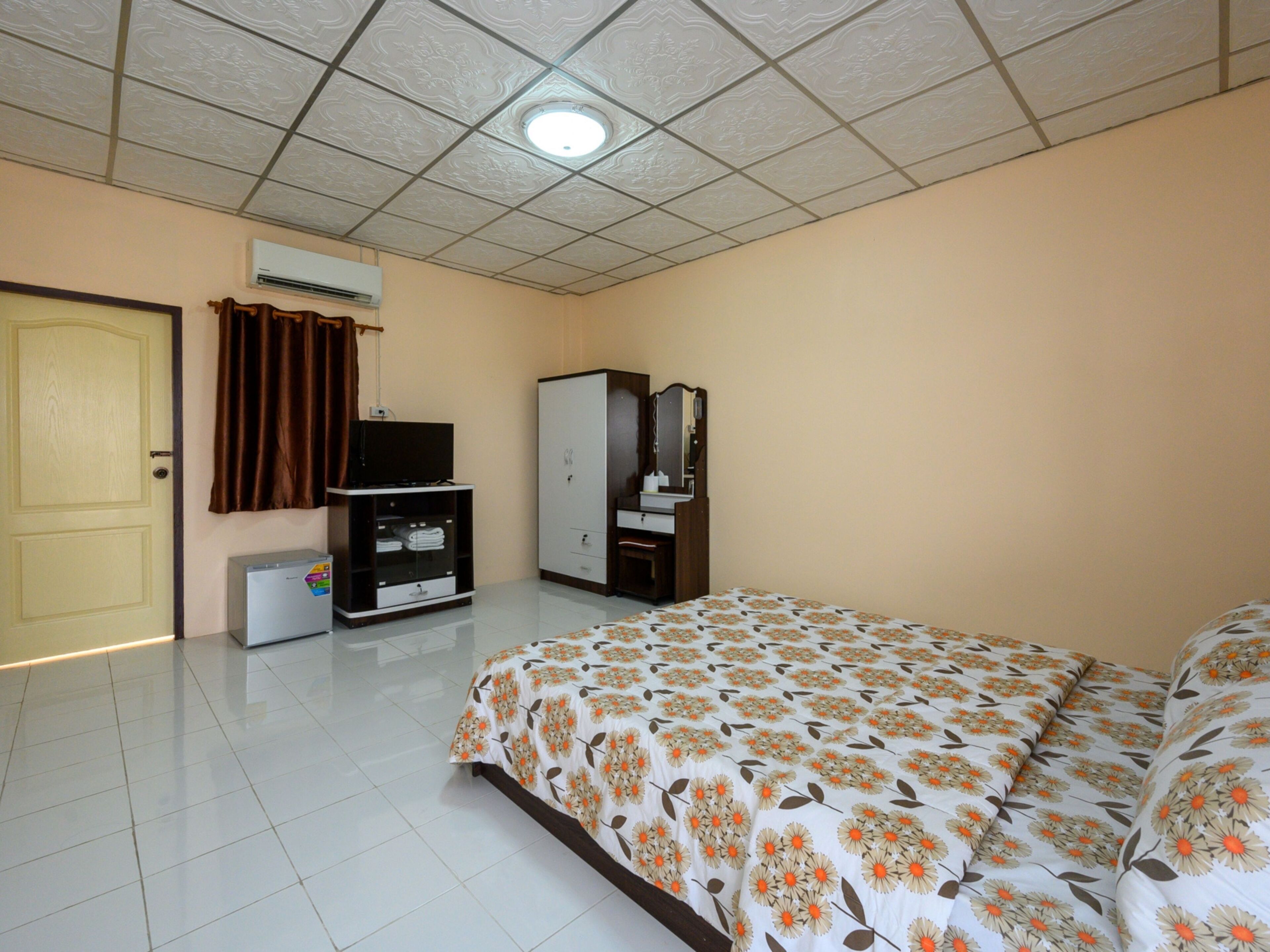 A bedroom with a bed, a wardrobe, a television, and an air conditioning unit.