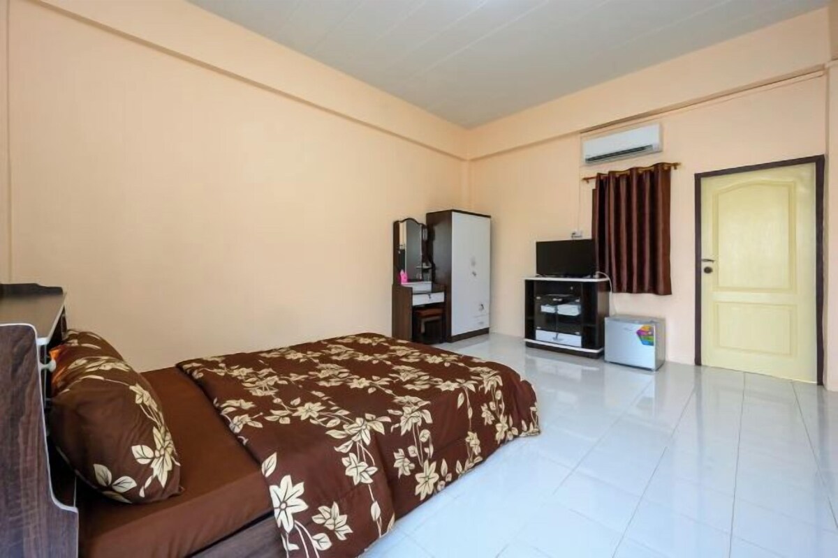Una habitación de hotel con cama, armario, televisor, aire acondicionado y puerta.