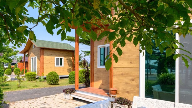 A modern wooden house with a porch, potted plants, and a paved driveway. - Beung Sampathuan Nakornchaisri Resort (Nakhon Chai Si)