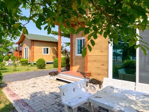 A modern wooden house with a porch, potted plants, and a paved driveway. - Beung Sampathuan Nakornchaisri Resort (Nakhon Chai Si)