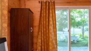 A wooden room with a sliding glass door leading to a patio area. - Beung Sampathuan Nakornchaisri Resort (Nakhon Chai Si)