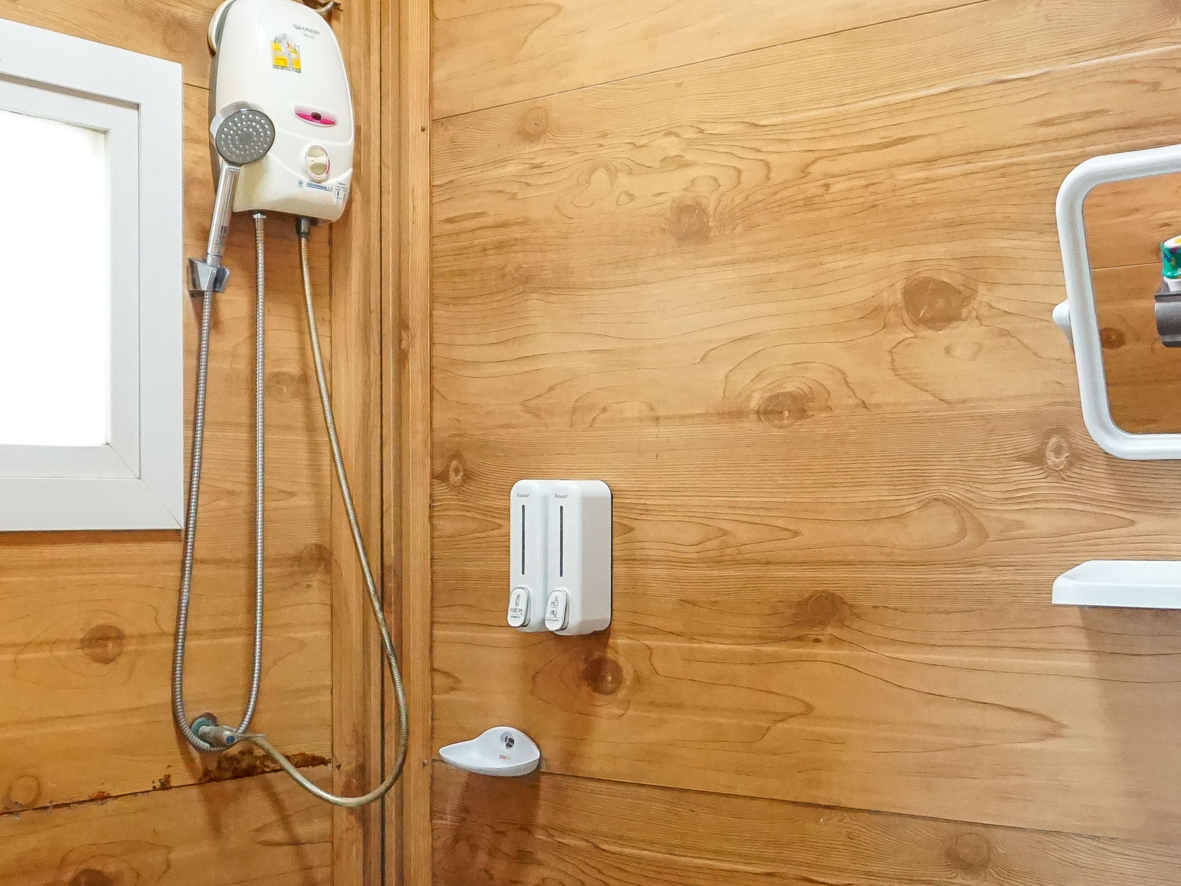 A bathroom with a wooden wall, a white showerhead, and a white towel warmer.
