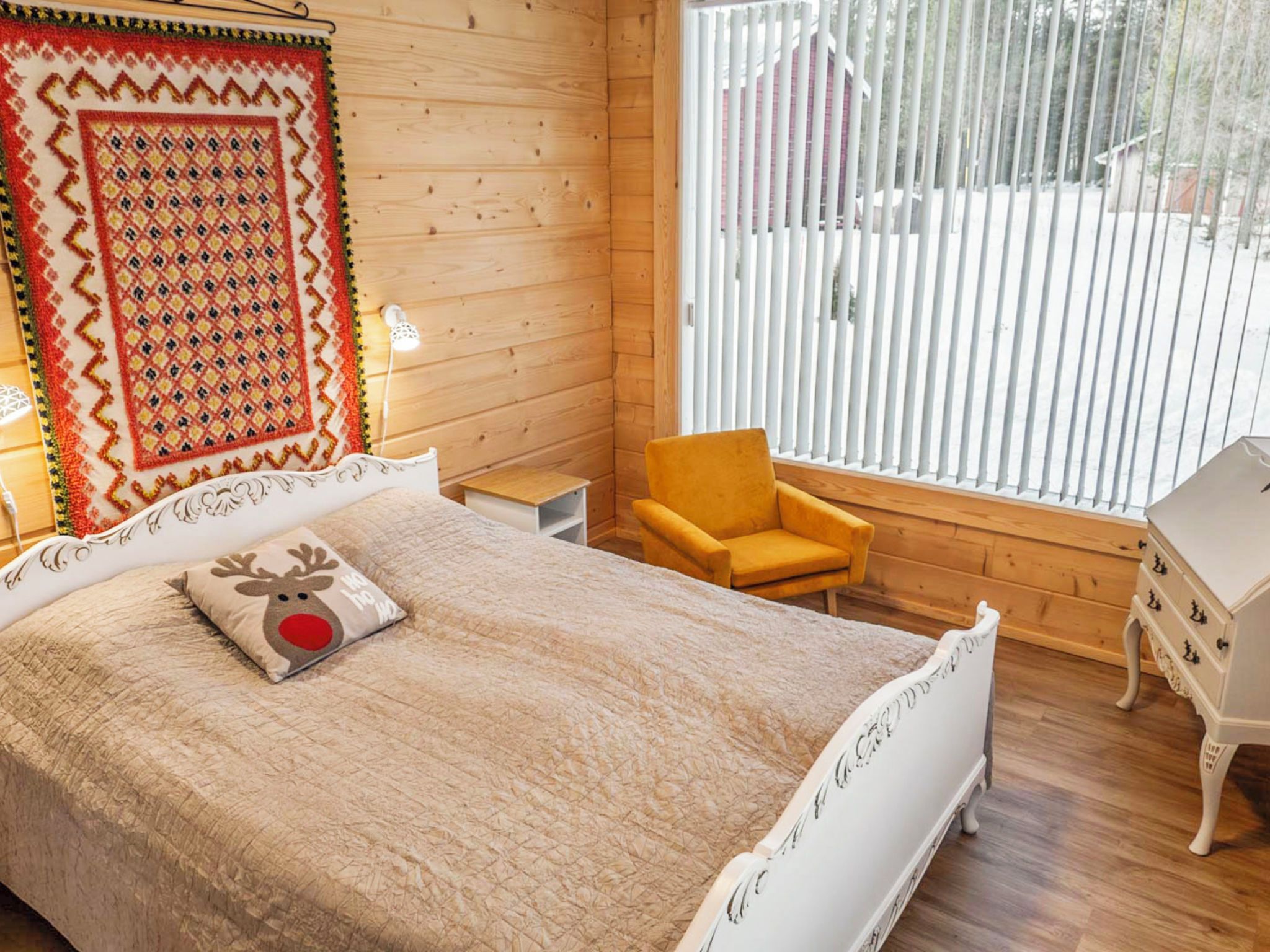 A cozy bedroom with a bed, a chair, a dresser, and a window with blinds.