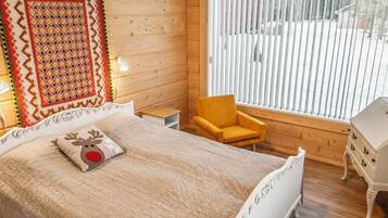 A cozy bedroom with a bed, a chair, a dresser, and a window with blinds.