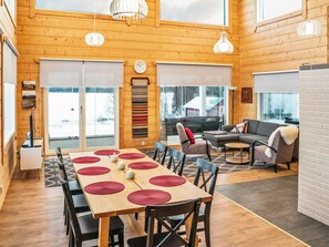 A spacious room with a wooden interior, a dining table with red placemats, and a sofa set.