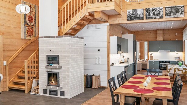 A spacious living area with a fireplace, wooden staircase, and a dining table with red placemats.