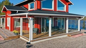 A modern two-story house with large glass windows and a covered patio area.