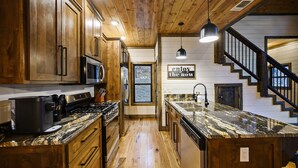 A kitchen with wooden cabinets, a granite countertop, and a stainless steel stove. - Secluded 2 Acres • 2 King Suites • Hot Tub • Sleeps 4–8 (Broken Bow)