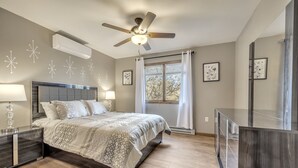 Ein Schlafzimmer mit Bett, Nachttischen, Deckenventilator und einem Fenster mit Vorhängen.