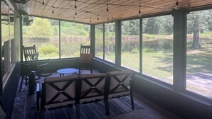 Eine überdachte Terrasse mit Seeblick, Holzboden und Gartenmöbeln.