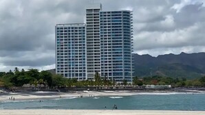 Un hotel frente a la playa con diseño moderno, que cuenta con un edificio destacado de techo plano y múltiples balcones.