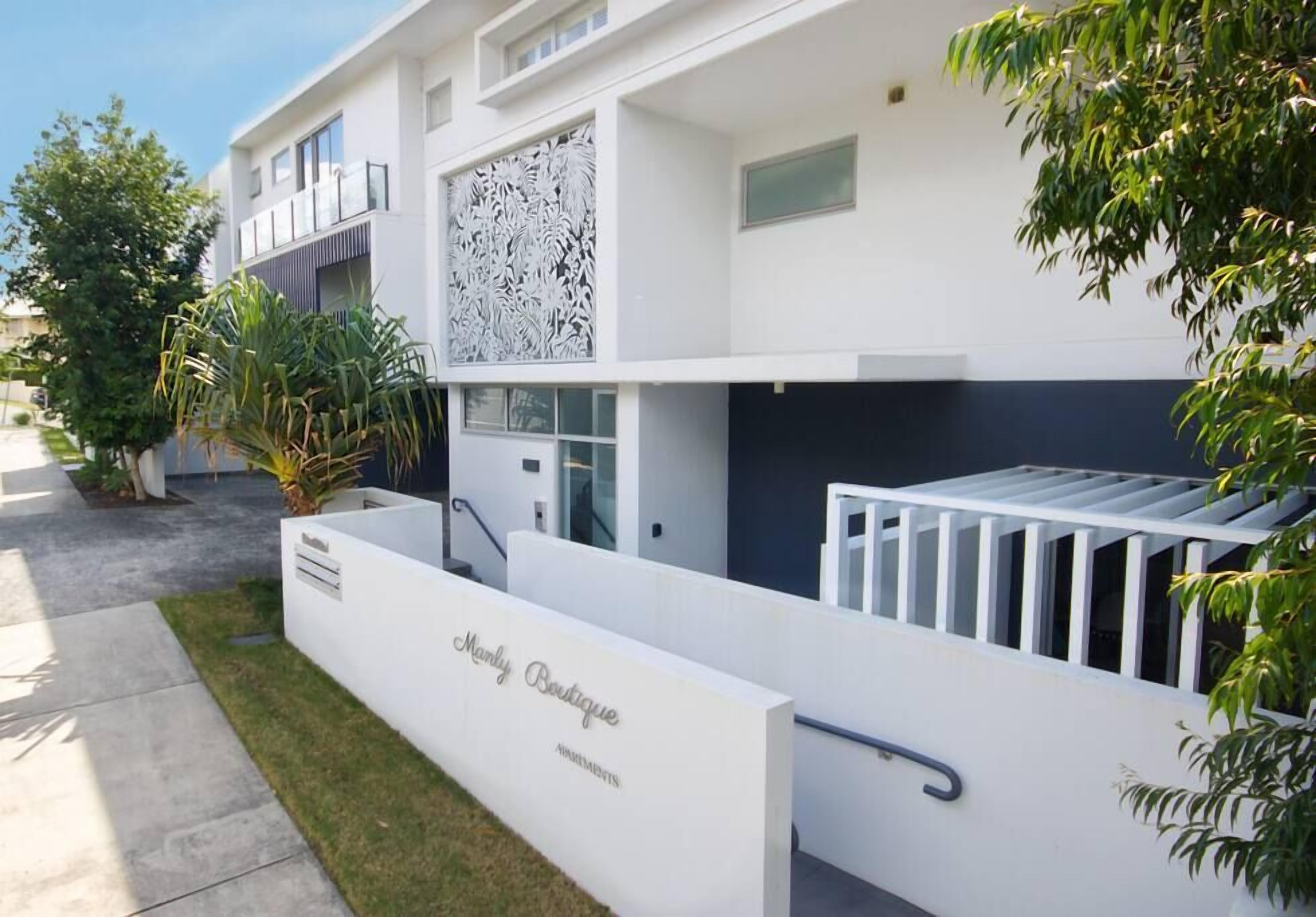 Un edificio moderno con fachada blanca, un letrero que dice "Marly Boutique" y una escalera que conduce a un nivel superior.