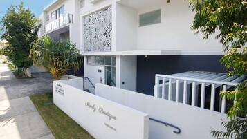 Un edificio moderno con fachada blanca, un letrero que dice "Marly Boutique" y una escalera que conduce a un nivel superior.