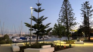 A marina with boats docked, surrounded by trees and modern outdoor seating areas.