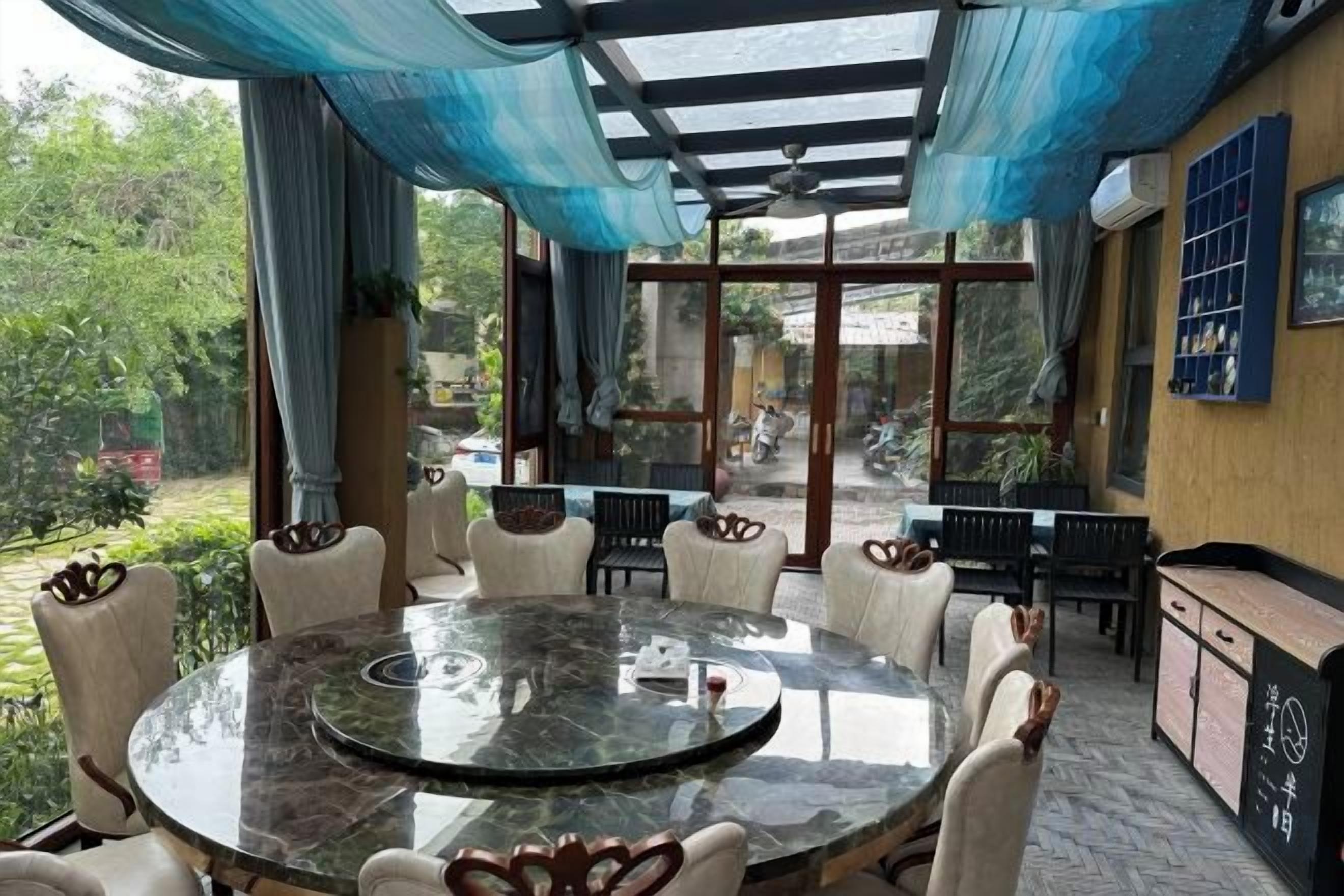 A round table with chairs in a room with a view of the outdoors.