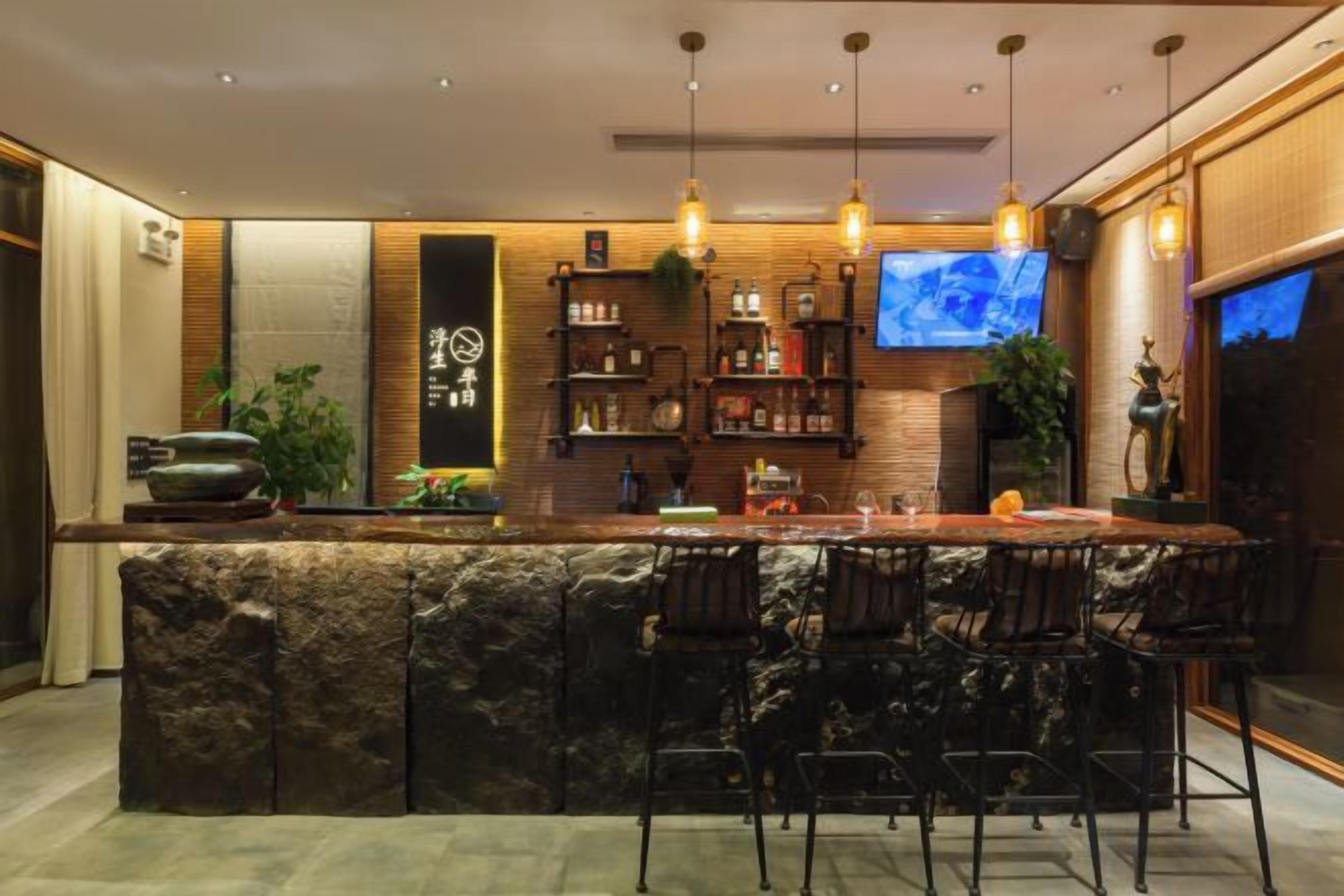 A modern bar area with a stone countertop, bar stools, and a television screen.