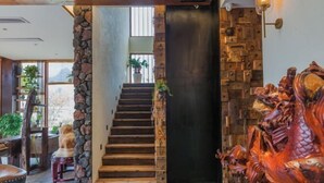 Una scala con un pilastro in pietra, gradini in legno e un muro decorativo con una scultura di drago.