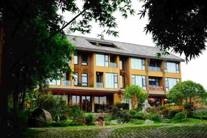 A multi-story building with a garden in front, featuring a mix of modern and traditional architectural elements. - Fusheng Banri Guesthouse (Guilin Zhujiang) (Guilin)