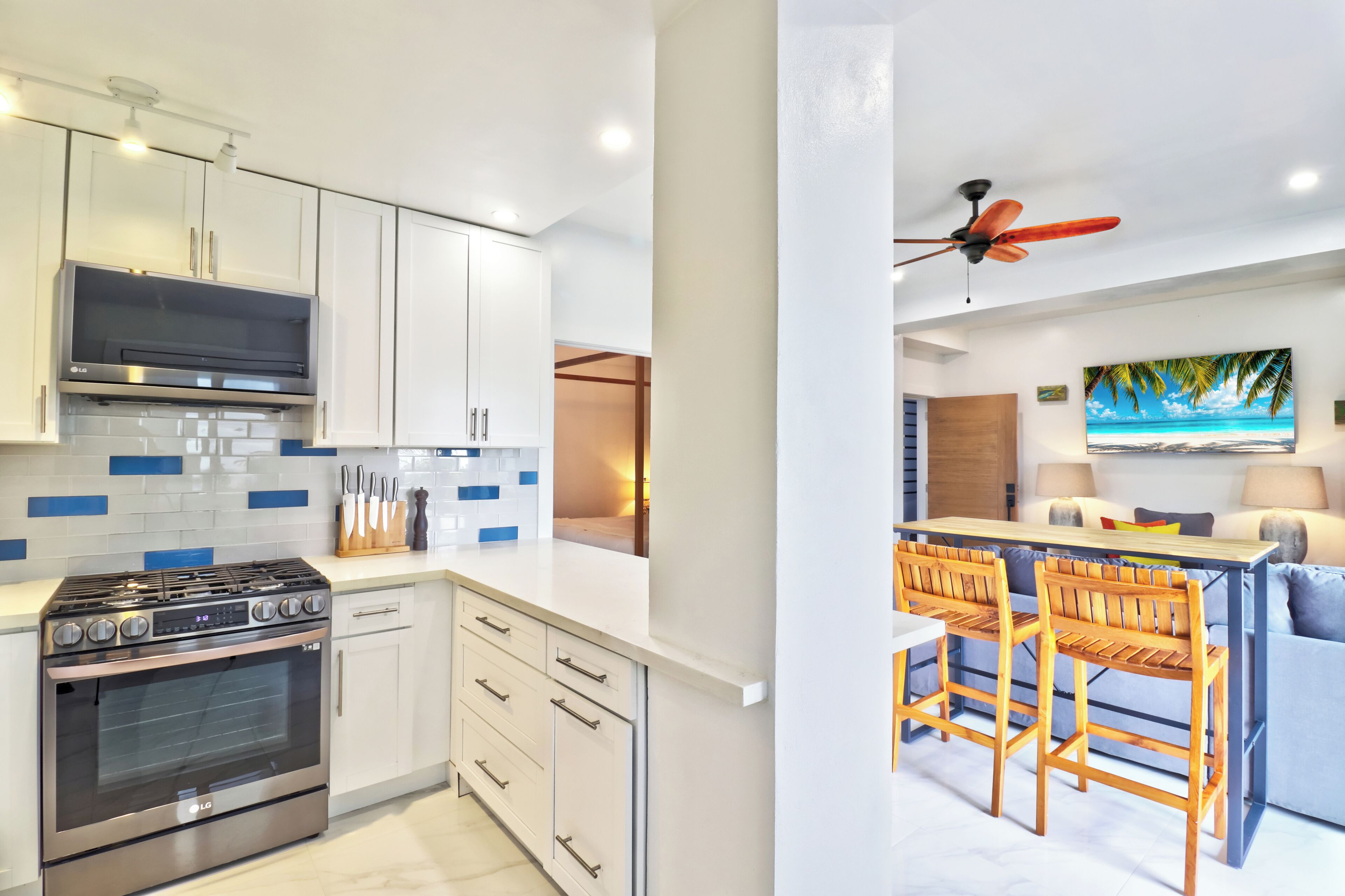A modern kitchen with an LG stove and oven, white cabinets, and blue tiles.